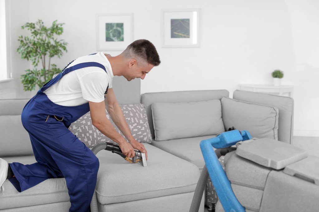 man vacuuming the sofa