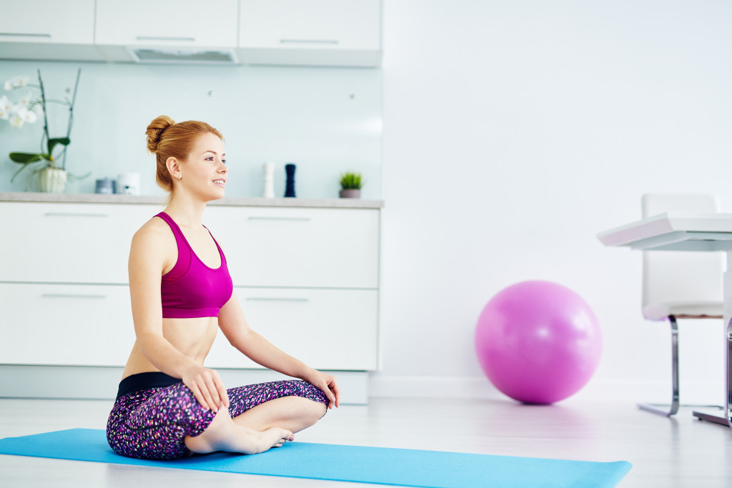 Portrait of fit red haired woman doing yoga exercises at home on floor