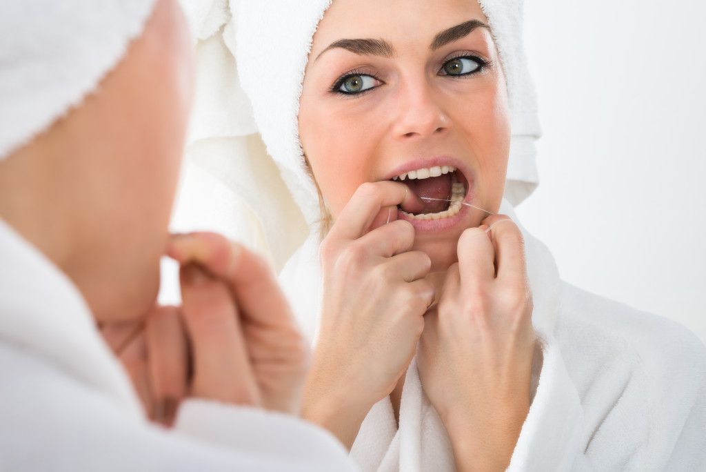 woman flossing after brushing teeth
