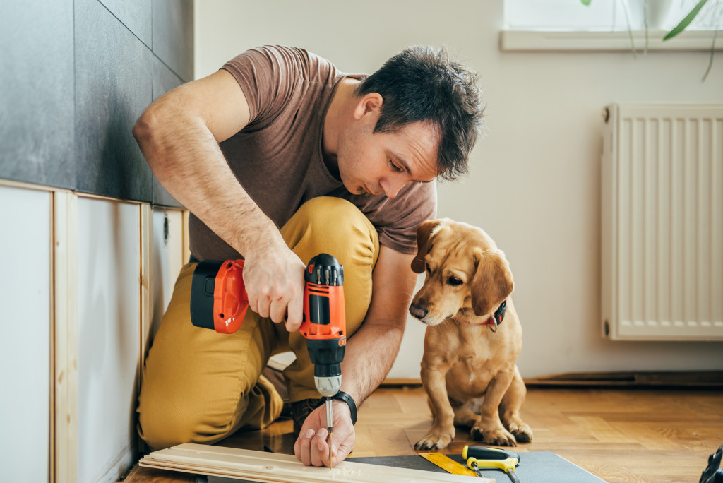 man drilling wood with dog