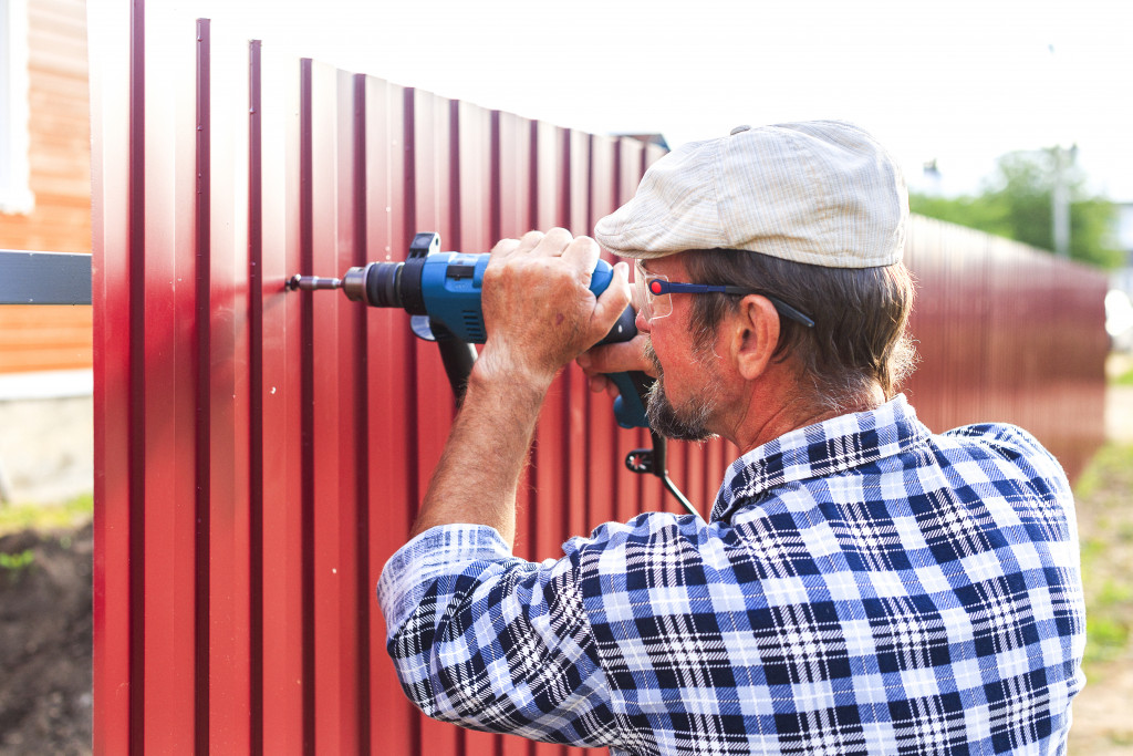 man installing metal fence around house