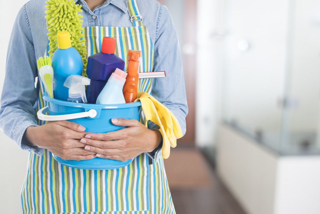 Person holds bucket full of cleaning supplies