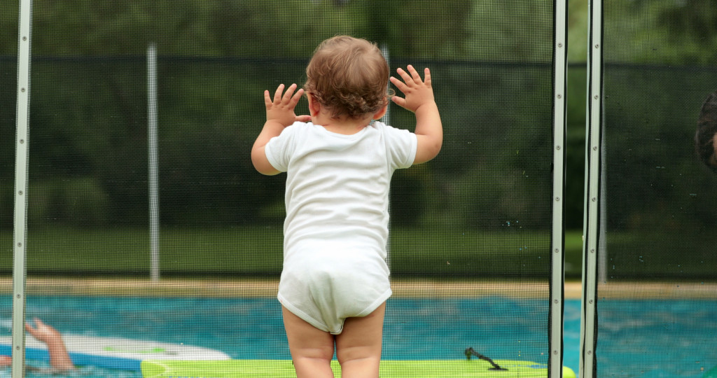 Baby lean on a fence protection near swimming pool 