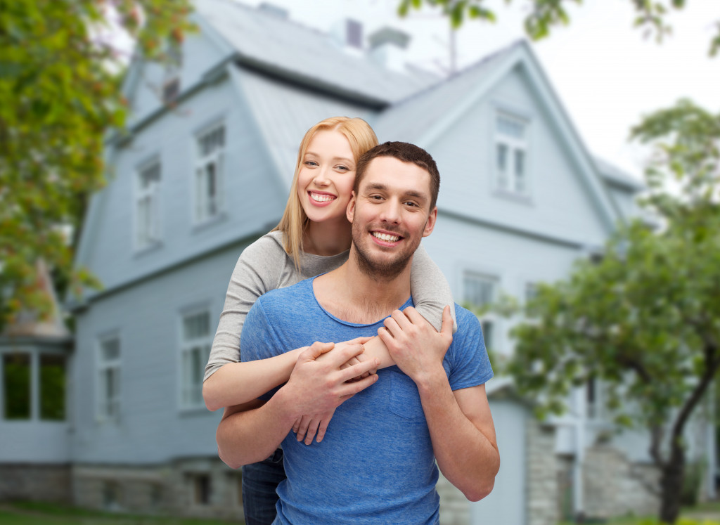 A married couple with their home in the background