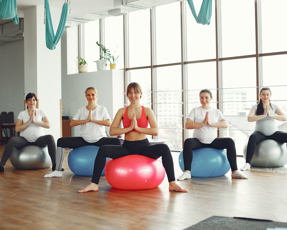 Cheerful group of pregnant women practicing yoga in modern studio