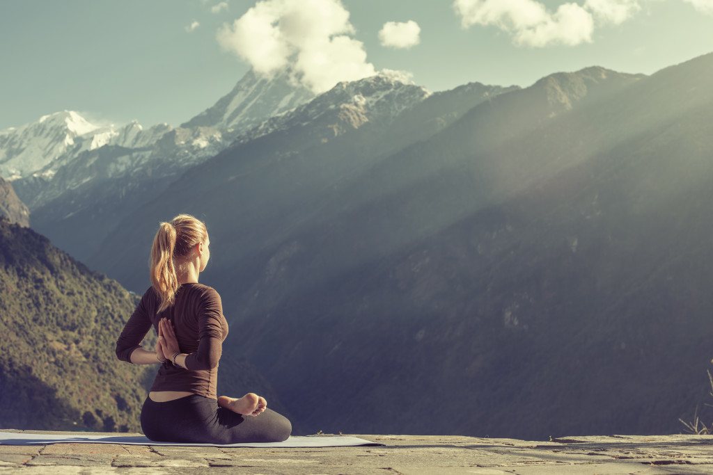 young girl doing yoga and meditation by the mountains