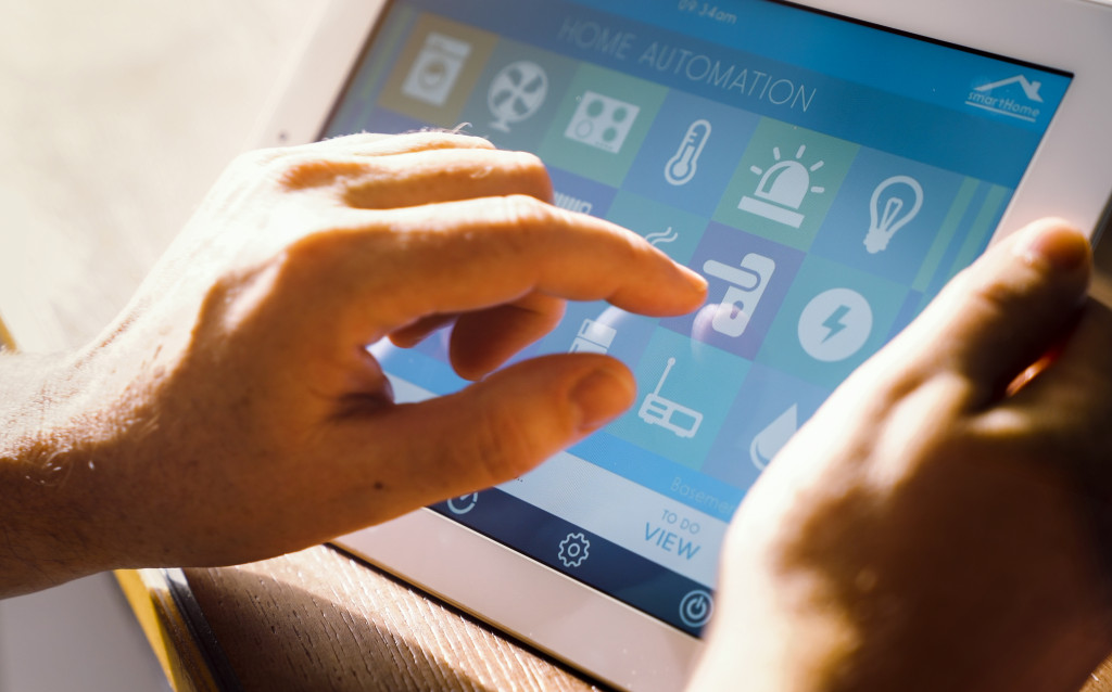 person's hand interacting with a tablet app controlling all smart home features