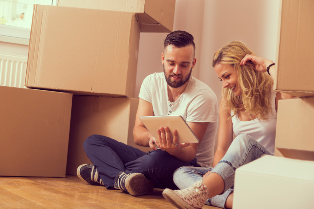 young couple moving in new apartment sitting on floor with boxes