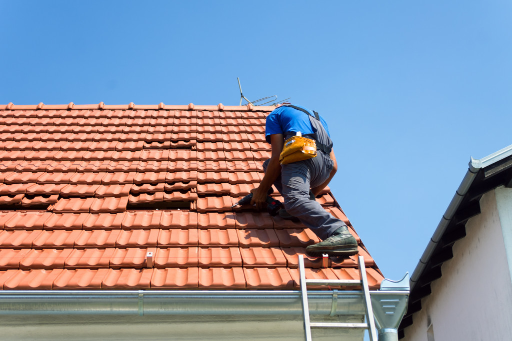 A worker installing roofing on a house