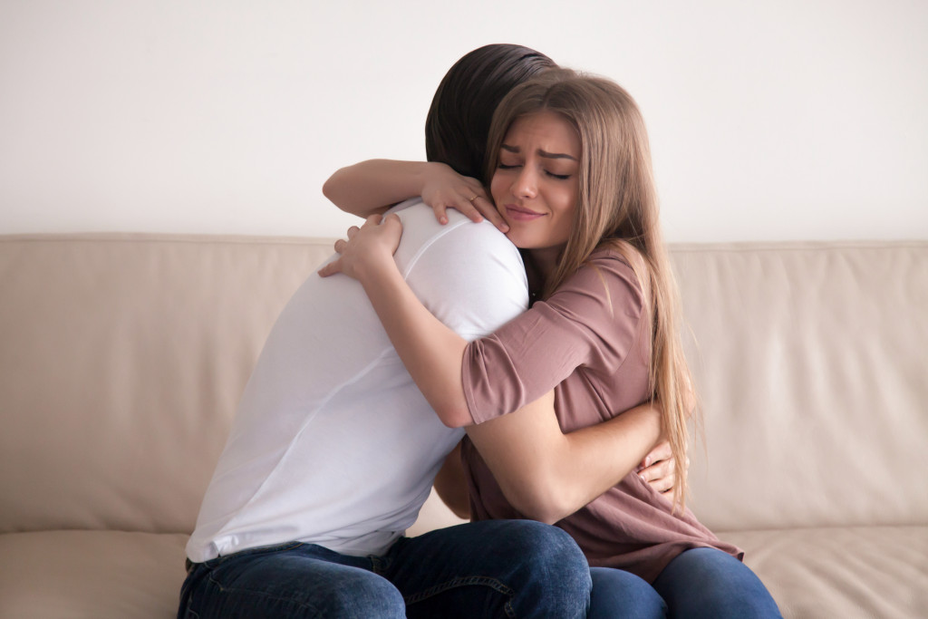 cute woman hugging her husband in the couch